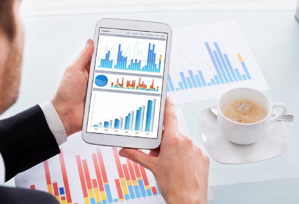 Cropped image of businessman comparing graphs on digital tablet at desk in office